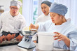 © Trevor Adeline/Caia Image - Young woman with Down Syndrome learning to bake in kitchen