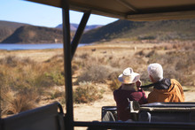 Senior Couple On Safari Looking At View Outside Off-road Vehicle