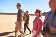 © Trevor Adeline/Caia Image - Safari tour guide and group walking in arid desert South Africa