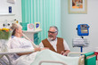 © Tom Merton/Caia Image - Affectionate senior man visiting, talking with wife resting in hospital room