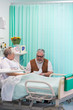 © Tom Merton/Caia Image - Senior man with greeting card visiting wife resting in hospital room