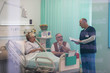© Tom Merton/Caia Image - Doctor with medical chart talking with senior couple in hospital room