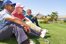 Male Golfers Resting Sitting In Grass On Sunny Golf Course