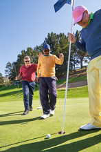 Male Golfers At Putting Green Hole