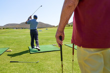 Male Golfer Practicing At Sunny Golf Course Driving Range