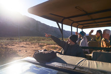 Safari Tour Guide And Group In Sunny Off-road Vehicle