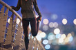 © Ryan Lees/Caia Image - Female runner stretching leg on footbridge at dusk