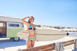 © Trevor Adeline/Caia Image - Young female surfer with surfboard on sunny summer beach