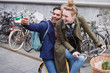 © Sam Edwards/Caia Image - Playful, laughing young couple taking selfie with camera phone on bicycle