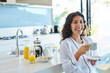 © Chris Ryan/Caia Image - Portrait laughing woman in bathrobe drinking coffee in morning kitchen