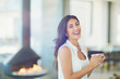 © Tom Merton/Caia Image - Portrait smiling woman drinking coffee near fireplace