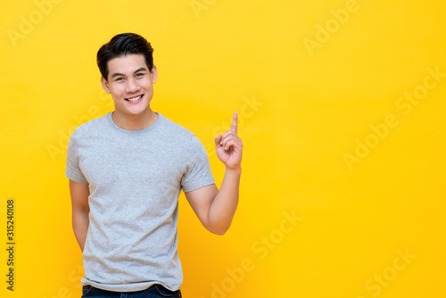 Cuadros en Lienzo Happy smiling young handnsome Asian man pointing hand up