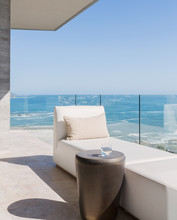 Chaise Lounge And Water Glass On Sunny Luxury Balcony With Ocean View