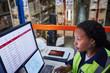 © Ryan Lees/Caia Image - Focused female manager using laptop and computer in distribution warehouse