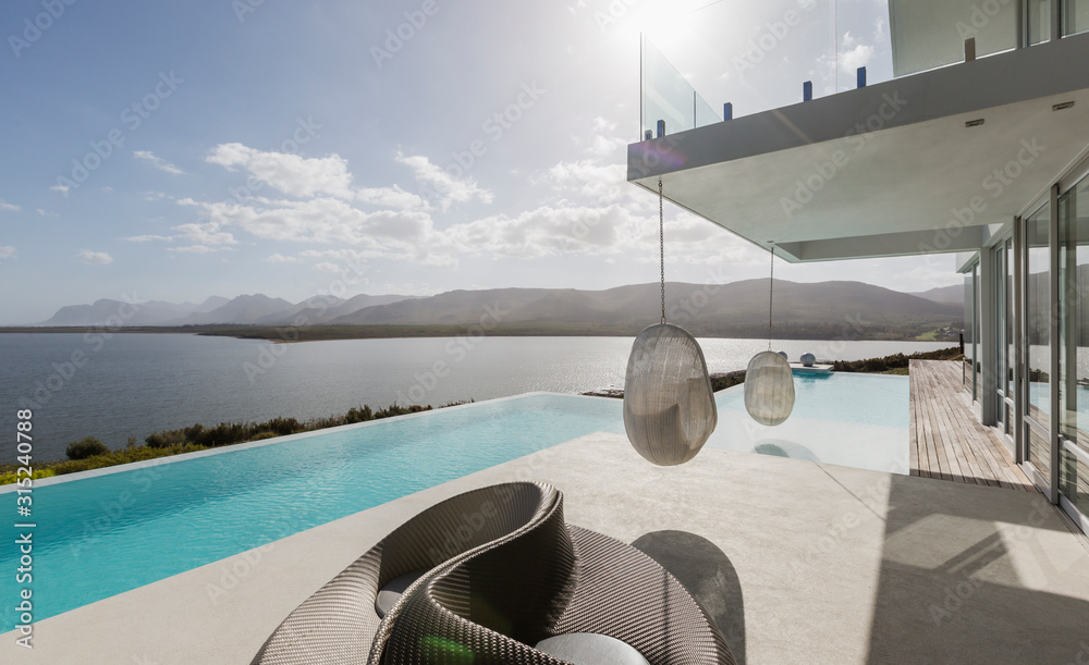 Sunny modern luxury home showcase exterior with infinity pool and ocean ...