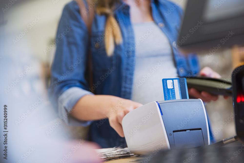 Female shopper using credit card reader in shop Stock Photo | Adobe Stock