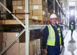 © Ryan Lees/Caia Image - Portrait smiling manager with clipboard next to shelf in distribution warehouse
