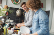 © Justin Pumfrey/Caia Image - Young men roommates cooking and doing dishes in kitchen