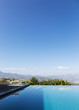 © Martin Barraud/Caia Image - Tranquil luxury infinity pool with mountain view below sunny blue sky