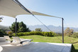 © Martin Barraud/Caia Image - Lounge chairs under awning on sunny patio with mountain view