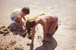© Sam Edwards/Caia Image - Brother and sister in bathing suit playing in wet sand on sunny summer beach