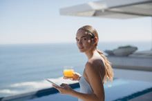 Portrait Woman Using Digital Tablet And Drinking Orange Juice On Sunny Luxury Patio With Ocean View