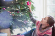 © Sam Edwards/Caia Image - Curious girl touching ornament on Christmas tree