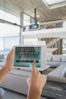 © Tom Merton/Caia Image - Personal perspective woman with digital tablet setting digital climate control in modern, luxury home showcase interior living room