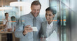 © Tom Merton/Caia Image - Smiling businessman and businesswoman watching video on smart phone in office