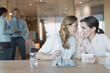 © Tom Merton/Caia Image - Businesswomen with digital tablets whispering in conference room meeting