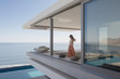 © Tom Merton/Caia Image - Woman looking at ocean view on modern, luxury home showcase exterior balcony