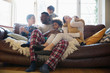© Sam Edwards/Caia Image - Young family relaxing in pajamas on living room sofa