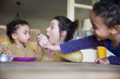 © Sam Edwards/Caia Image - Playful mother feeding baby son at table