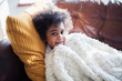 © Sam Edwards/Caia Image - Portrait cute girl relaxing, cuddling on sofa with blanket and pillow
