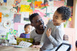 © Sam Edwards/Caia Image - Playful father and son laughing, coloring at dining table