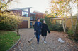 © Tom Merton/Caia Image - Couple walking dogs in autumn driveway