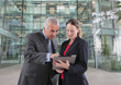 © Robert Daly/Caia Image - Business people using digital tablet outside modern office building