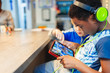 © Paul Bradbury/Caia Image - Boy with headphones and digital tablet playing video game