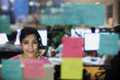 © Tom Merton/Caia Image - Businesswoman with headset working at computer in office behind adhesive notes