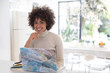 © Sam Edwards/Caia Image - Portrait happy young woman working at laptop in kitchen