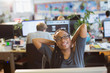 © Tom Merton/Caia Image - Portrait confident businesswoman stretching in open plan office