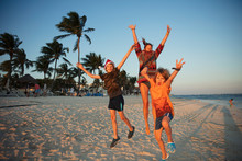 Portrait Carefree Family Jumping For Joy On Tropical Beach Mexico