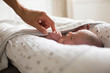 © Sam Edwards/Caia Image - Mother holding hands with newborn baby son in bassinet