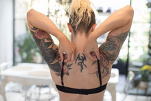 Woman With Tattooed Shoulders Adjusting Bra Straps