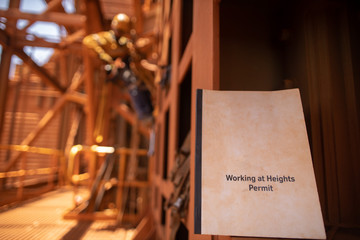Wall Mural - working at height permit booklet with defocused abseiler inspector working in fall restraint, descen