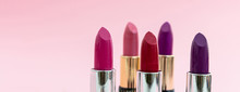 Lipsticks Various Colors Against Pink Background, Closeup View