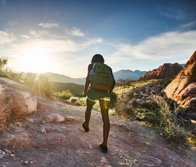 Wall Mural - athletic african american woman hiking through red rock canyon in nevada at sunset