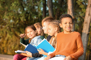 Sticker - Cute little children reading books in park