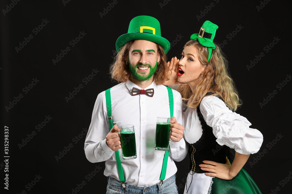 Young couple with beer on dark background. St. Patrick's Day celebration