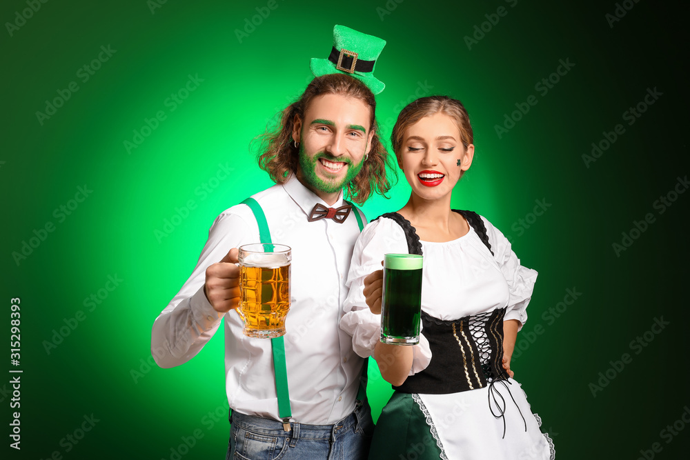 Young couple with beer on color background. St. Patrick's Day celebration
